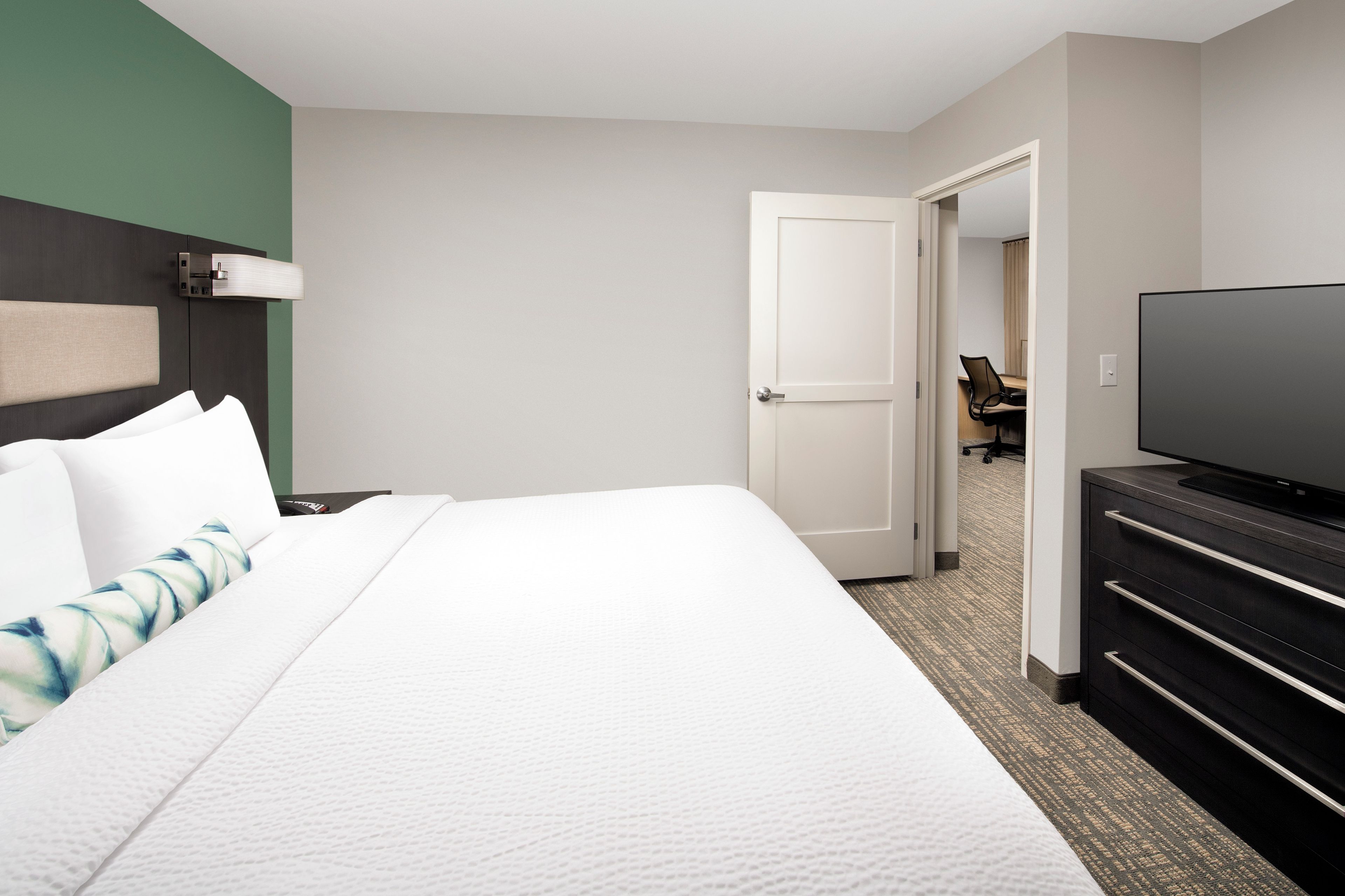 A hotel room with a bed, a television, a desk, and a chair.