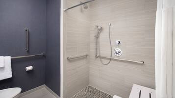 Un baño moderno con ducha, inodoro y barras de apoyo.