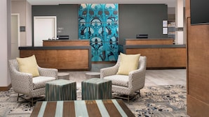 A reception area with two patterned armchairs, a reception desk, and a decorative wall. - Residence Inn by Marriott New Orleans Elmwood (New Orleans)