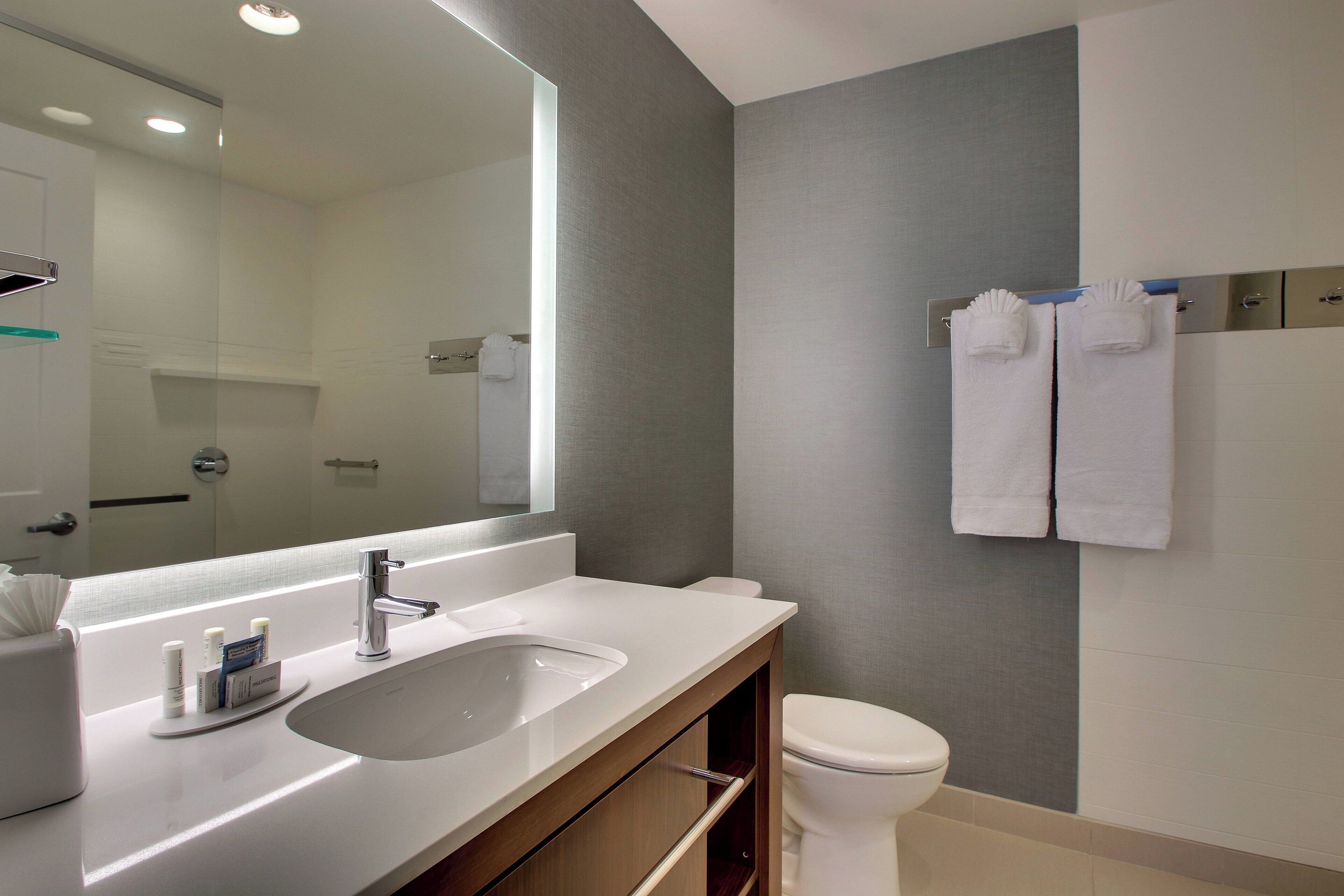A modern bathroom with a large mirror, a sink, and a toilet.