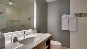 A modern bathroom with a large mirror, a sink, and a toilet.