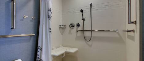 Un baño moderno con ducha, inodoro y barras de apoyo.