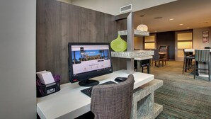 A hotel reception desk with a computer monitor displaying a webpage, a green vase, and a modern interior design. - Residence Inn Valley Forge/Collegeville (Collegeville)