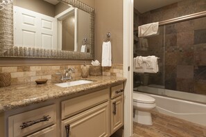 A bathroom with a sink, mirror, towel rack, and a bathtub.