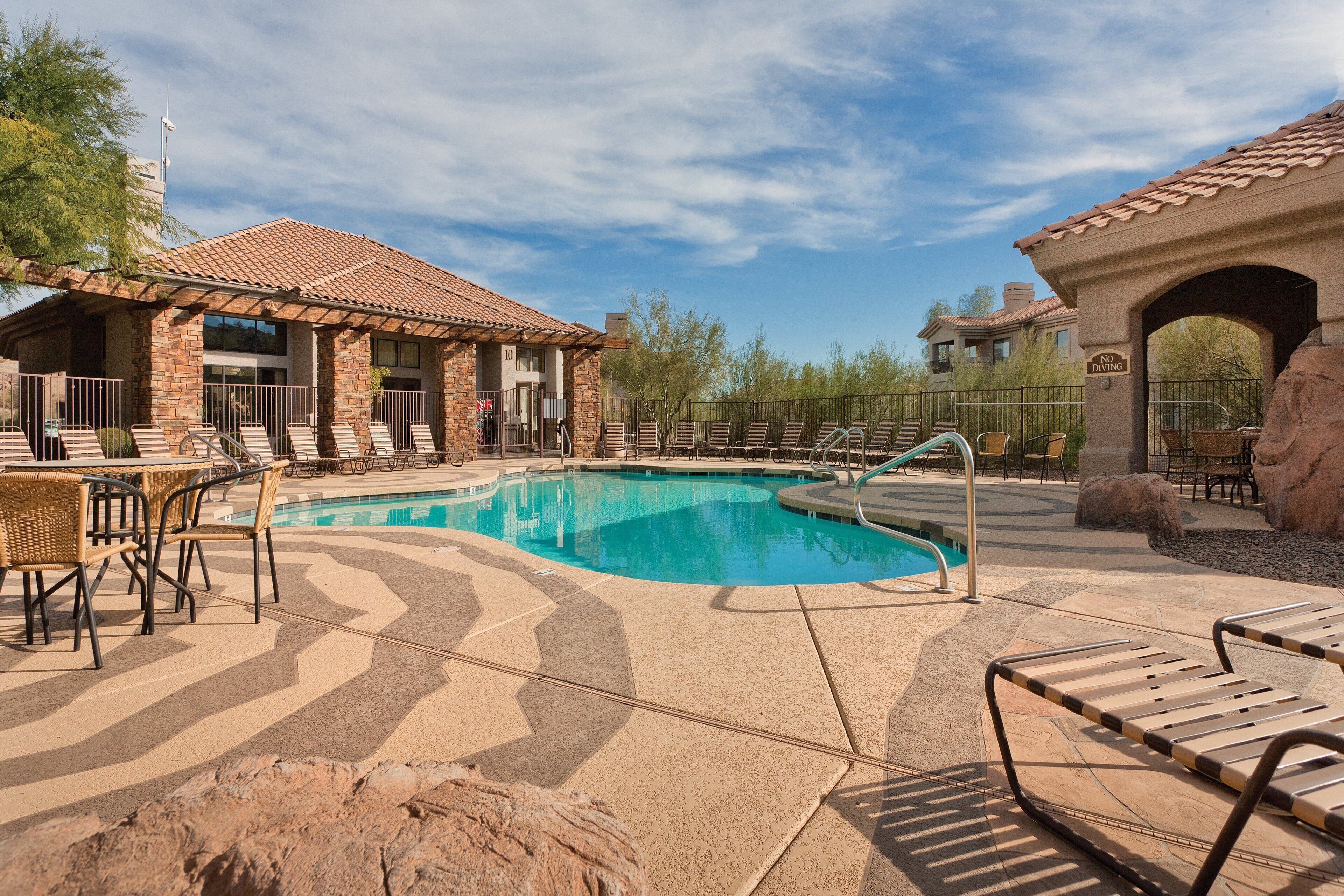 A pool area with lounge chairs, a covered seating area, and a 'No Diving' sign.