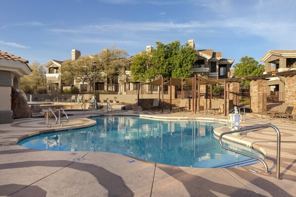A swimming pool with a stone deck, lounge chairs, and a pergola structure. - WorldMark Phoenix - South Mountain Preserve (Phoenix)