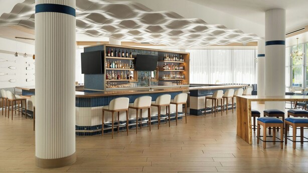 A bar area with a central bar, multiple seating arrangements, and a patterned ceiling. - Maritime Hotel Fort Lauderdale Airport & Cruiseport (Fort Lauderdale)