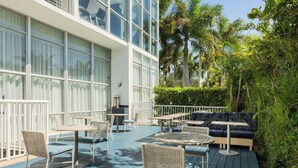 An outdoor patio with tables and chairs, a sofa, and a railing. - Maritime Hotel Fort Lauderdale Airport & Cruiseport (Fort Lauderdale)