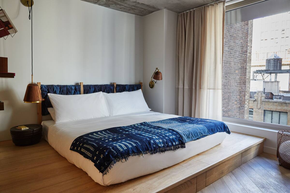 Un dormitorio con una cama grande, vistas a la ciudad y una lámpara moderna.