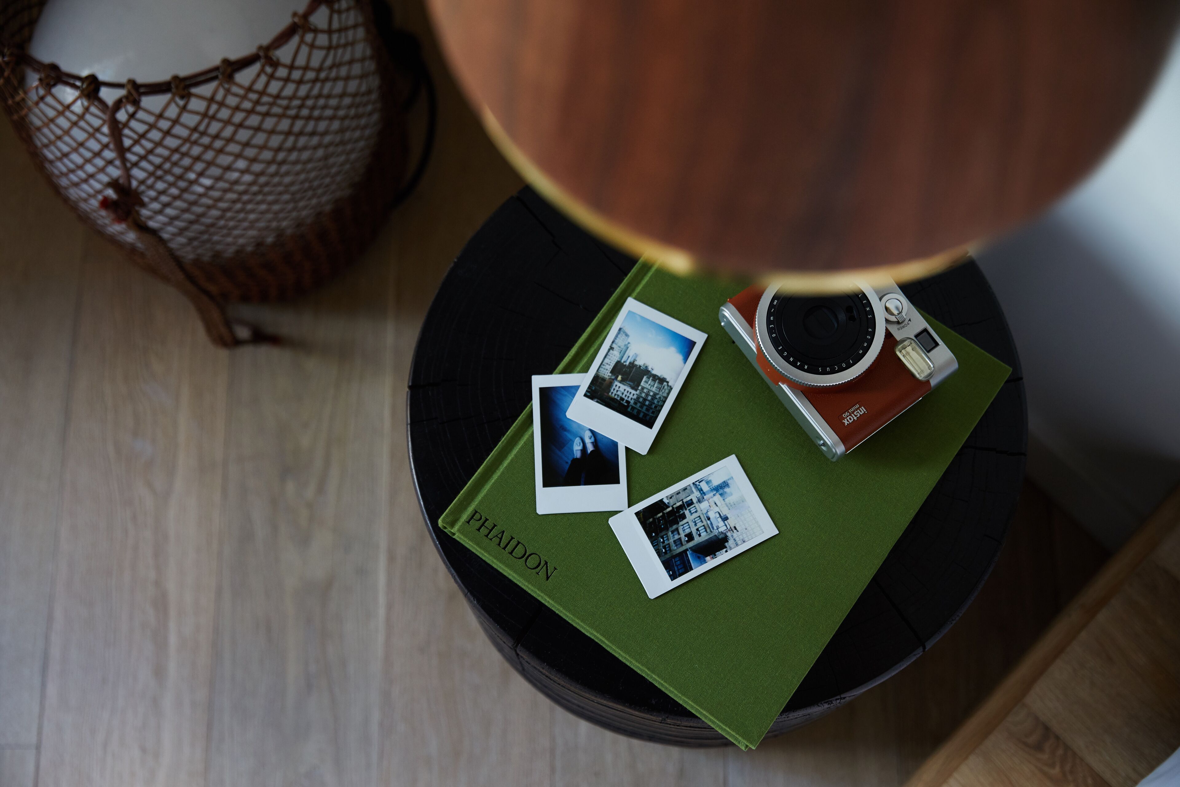 Ein runder Tisch mit grüner Oberfläche, ein Buch mit dem Titel 'Phaidon' und zwei Fotografien.
