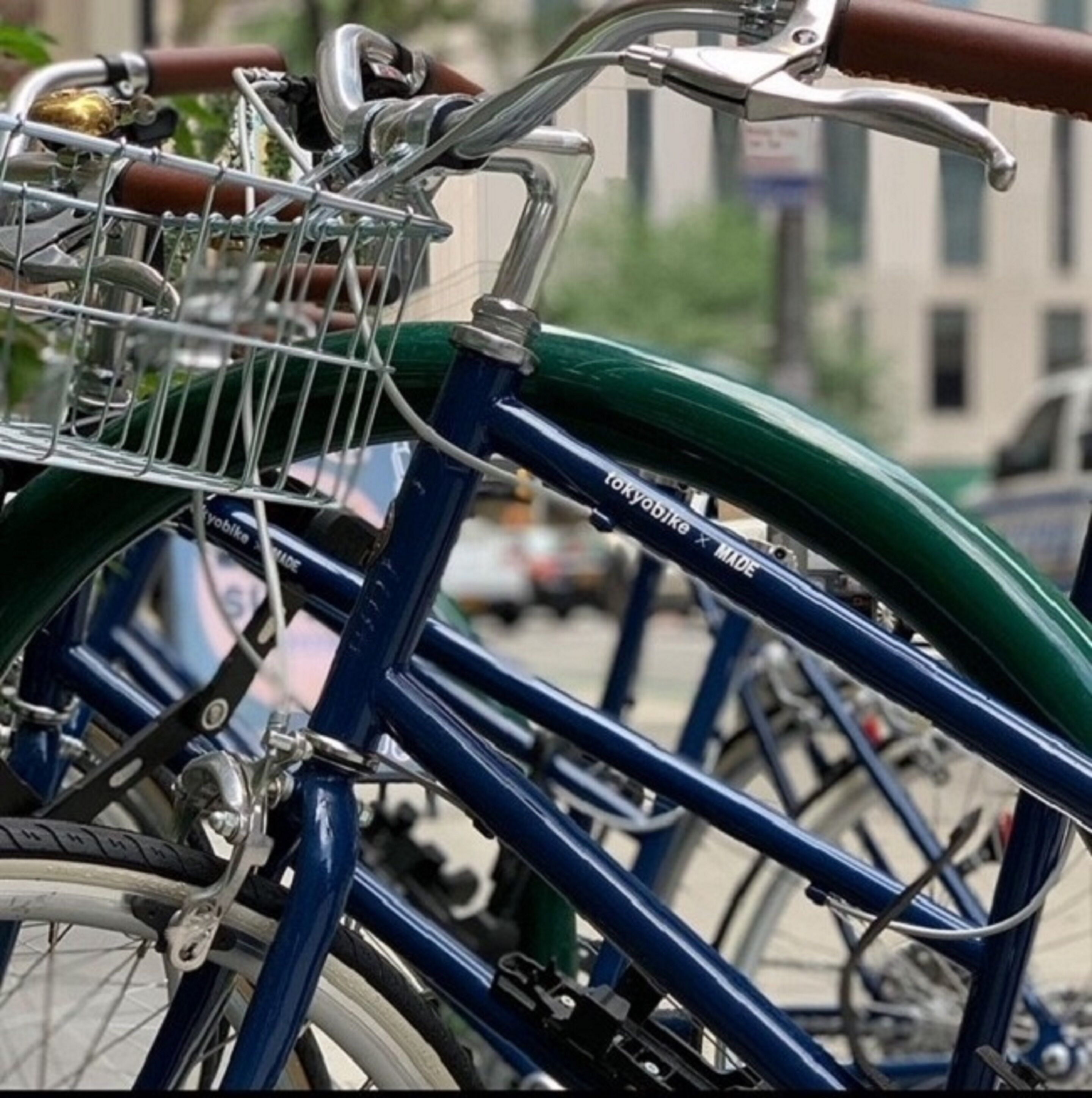 A blue bicycle with a basket and a green frame, parked on a street.