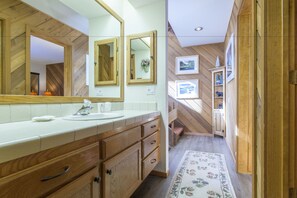 A bathroom with wooden cabinetry, a large mirror, and a tiled floor. - Snowcreek 474 Phase III (Mammoth Lakes)