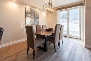 A dining area with a wooden table and four chairs, a modern chandelier, and a large abstract painting on the wall. - Snowcreek 754 Phase V (Mammoth Lakes)