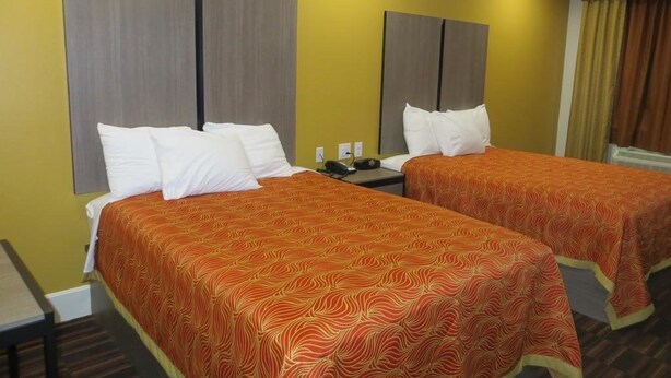 Quarto de hotel com duas camas, cada uma com colcha estampada e almofadas brancas.