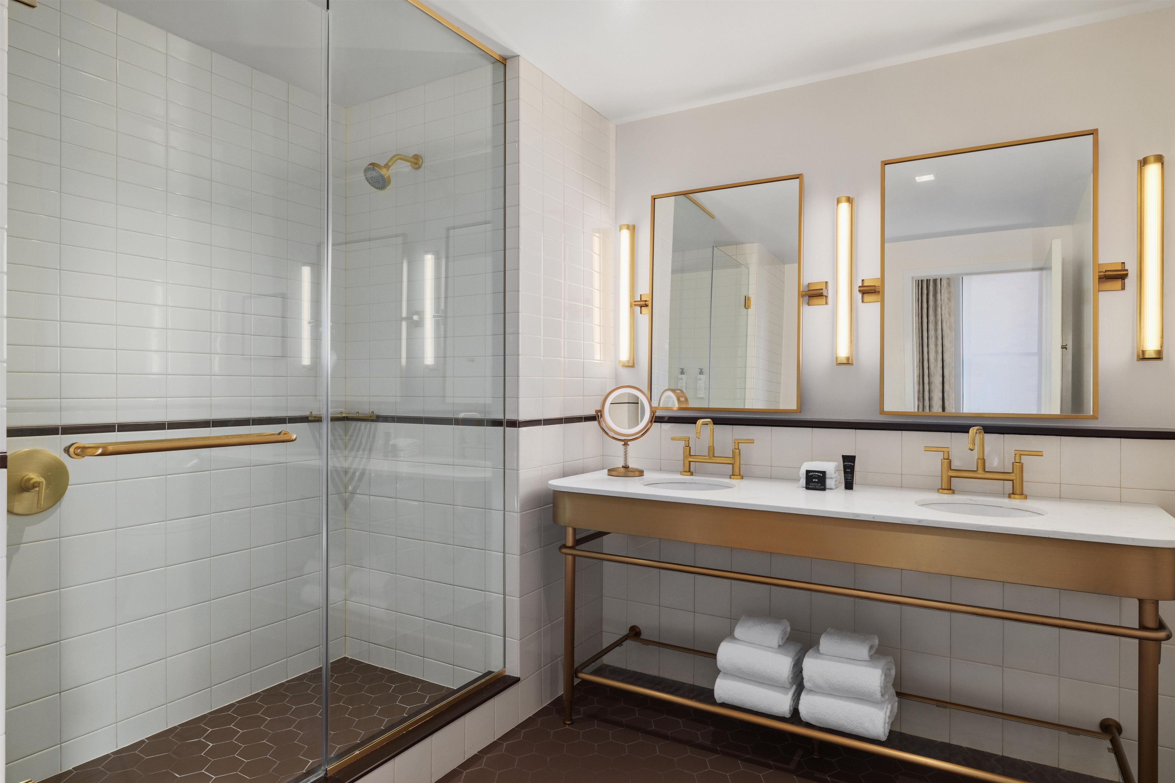 A modern bathroom with a glass-enclosed shower, a vanity with gold fixtures, and a mirror with a gold frame.