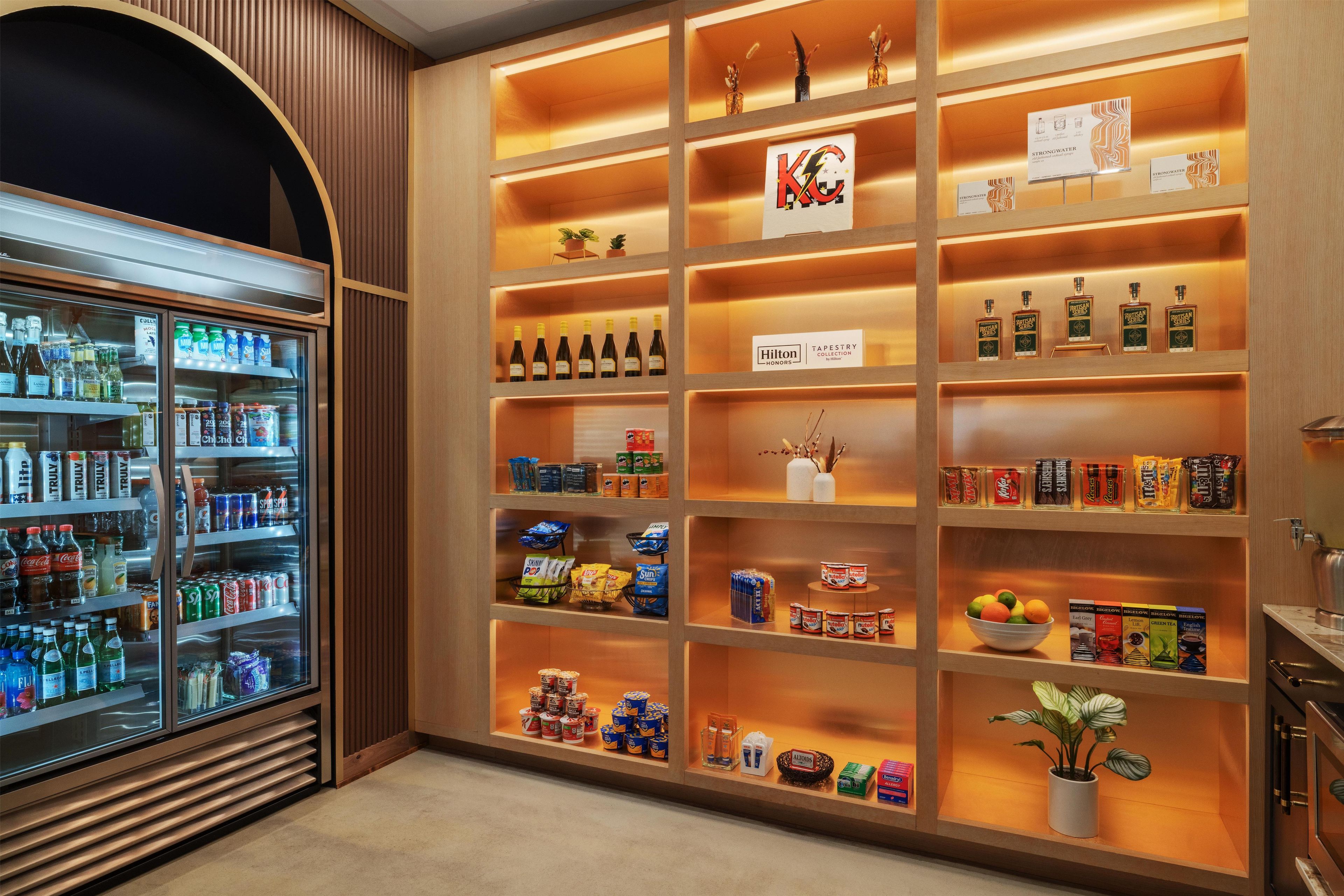 Un minibár de hotel con diferentes bebidas, aperitivos y condimentos.