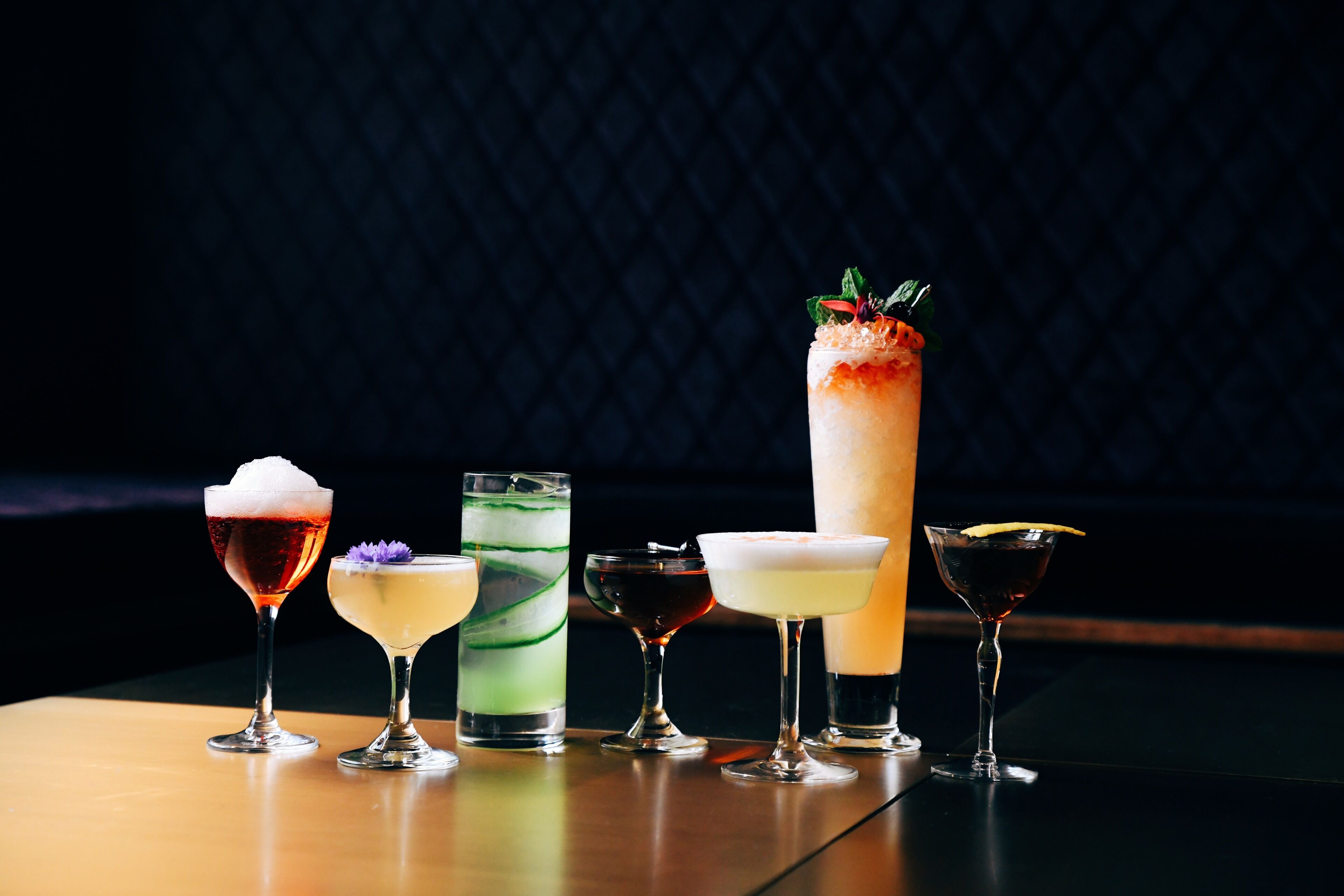 A variety of cocktails on a table with a dark background.