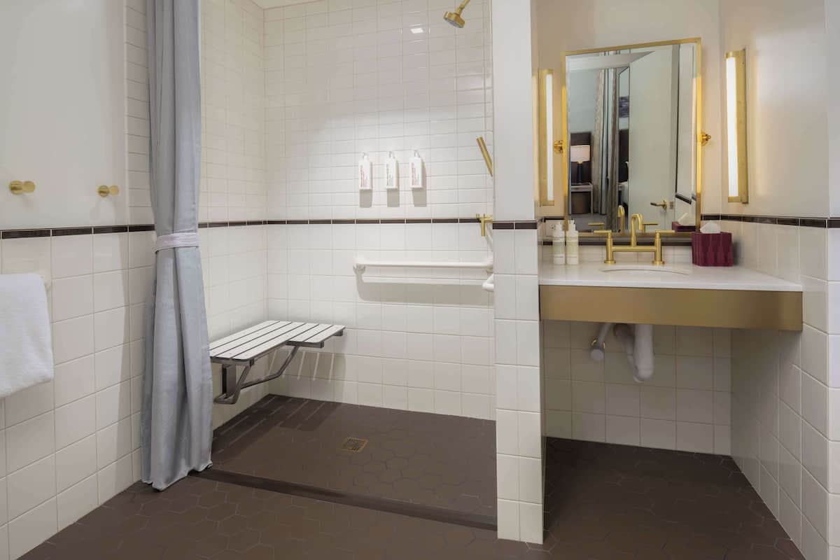 Une salle de bain moderne avec des murs recouverts de carreaux blancs, un espace douche, un meuble-lavabo avec un miroir et un porte-serviettes.
