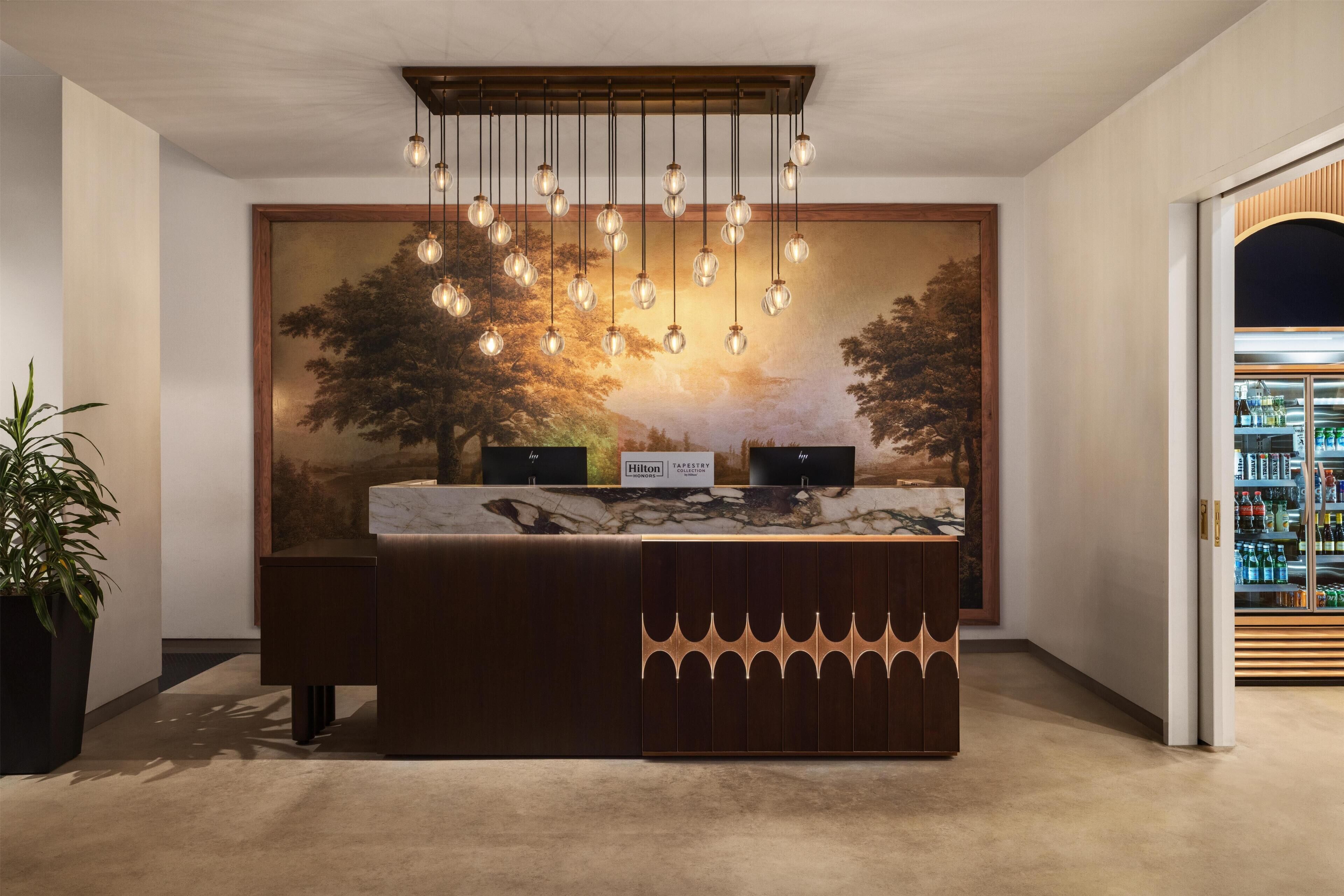 Bancada de recepção com superfície de mármore, um quadro grande com paisagem e um minibar.