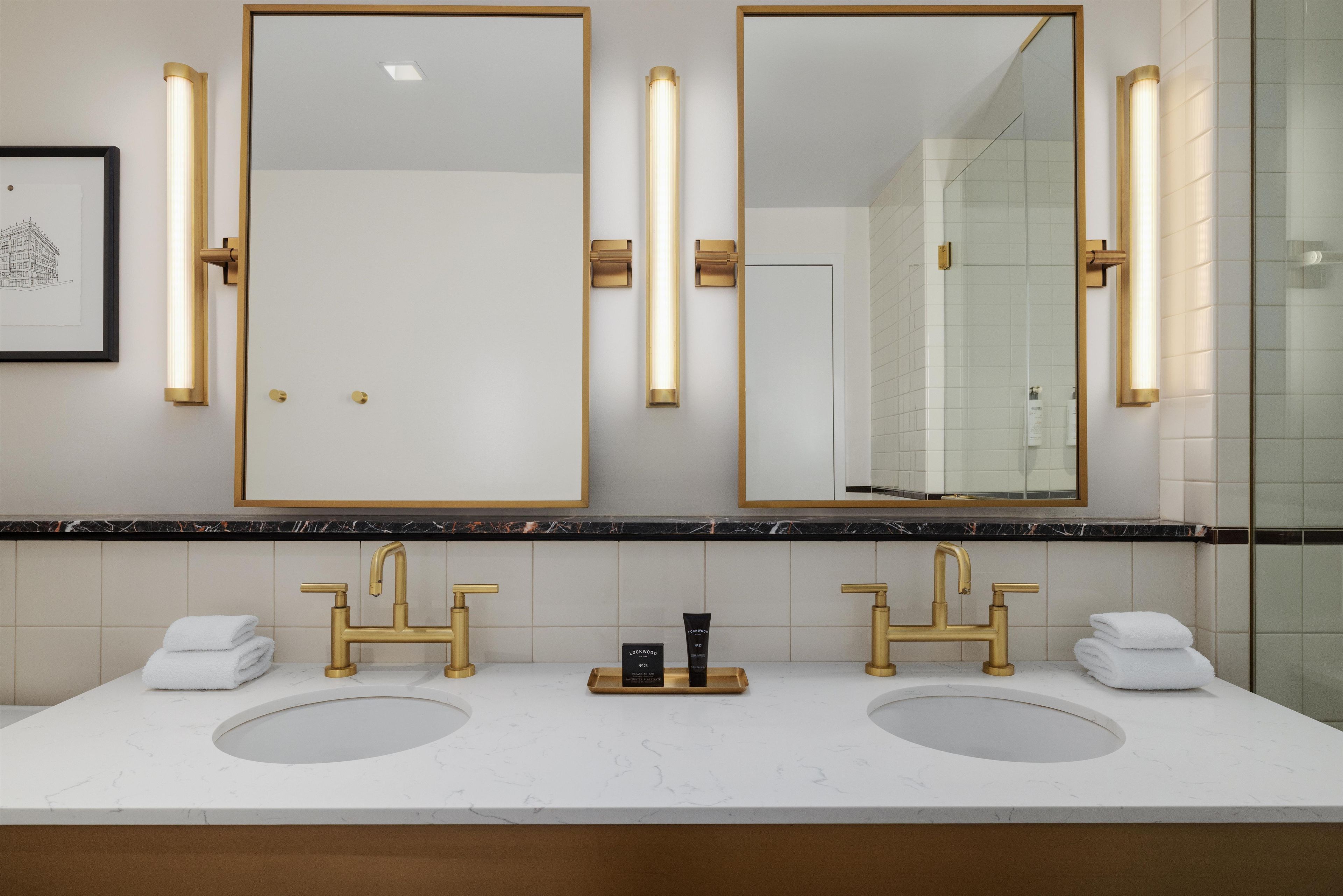 Une salle de bain avec deux lavabos, un miroir encadré et des luminaires fixés au mur.