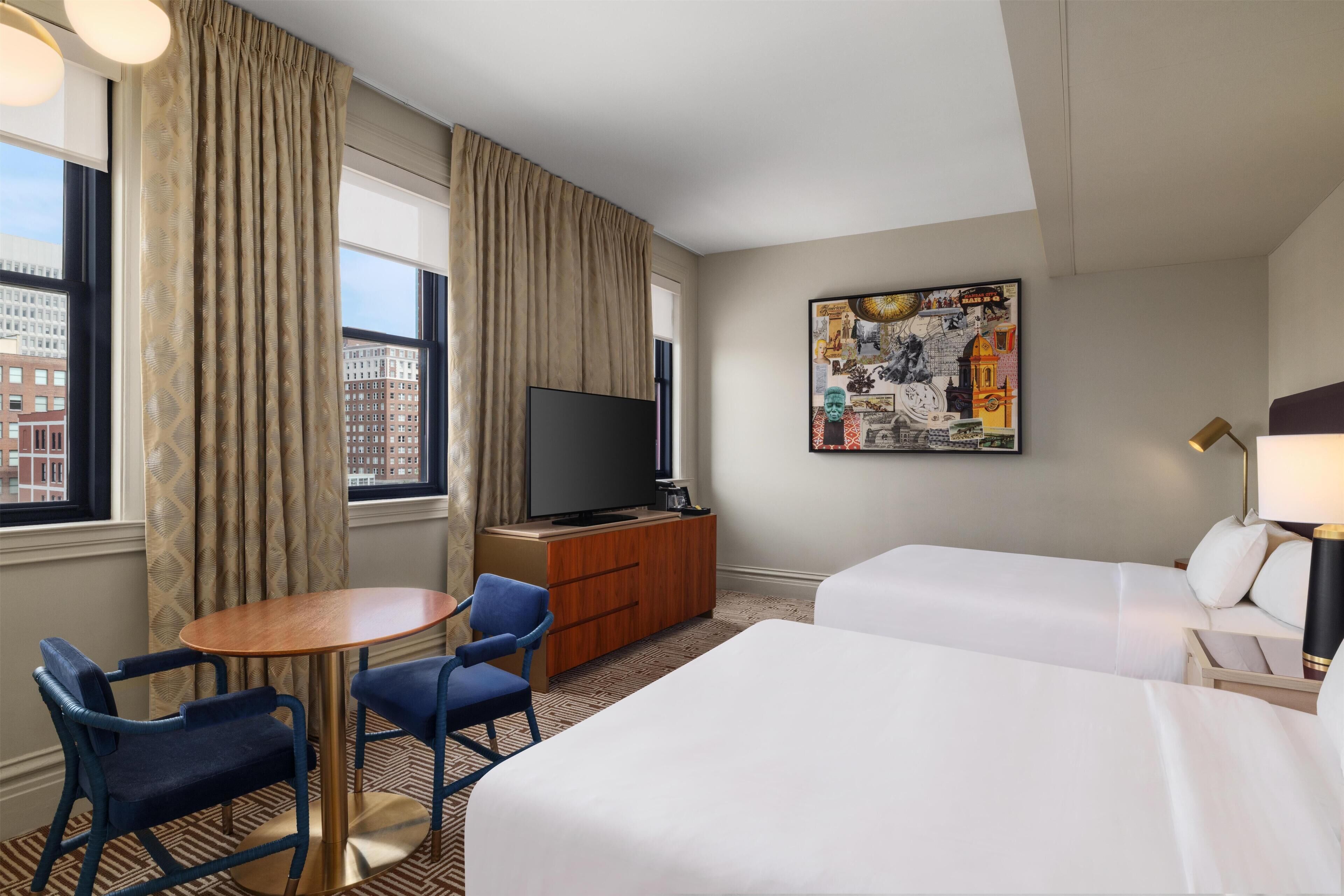 Een hotelkamer met een bed, een bureau, een stoel, een televisie en een kunstwerk aan de muur.