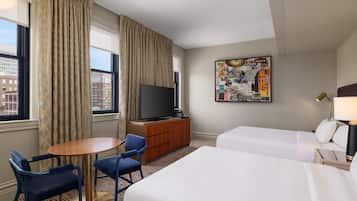 Een hotelkamer met een bed, een bureau, een stoel, een televisie en een kunstwerk aan de muur.