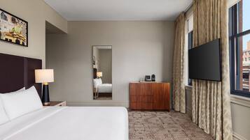 Una habitación de hotel con una cama grande, un televisor de pantalla plana, un aparador de madera y una alfombra estampada.