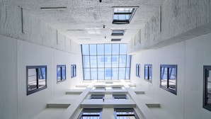 A spacious atrium with high ceilings and skylights, featuring a central open area with multiple windows and a symmetrical layout. - Hotel Savoy Kansas City, Tapestry Collection by Hilton (Kansas City)