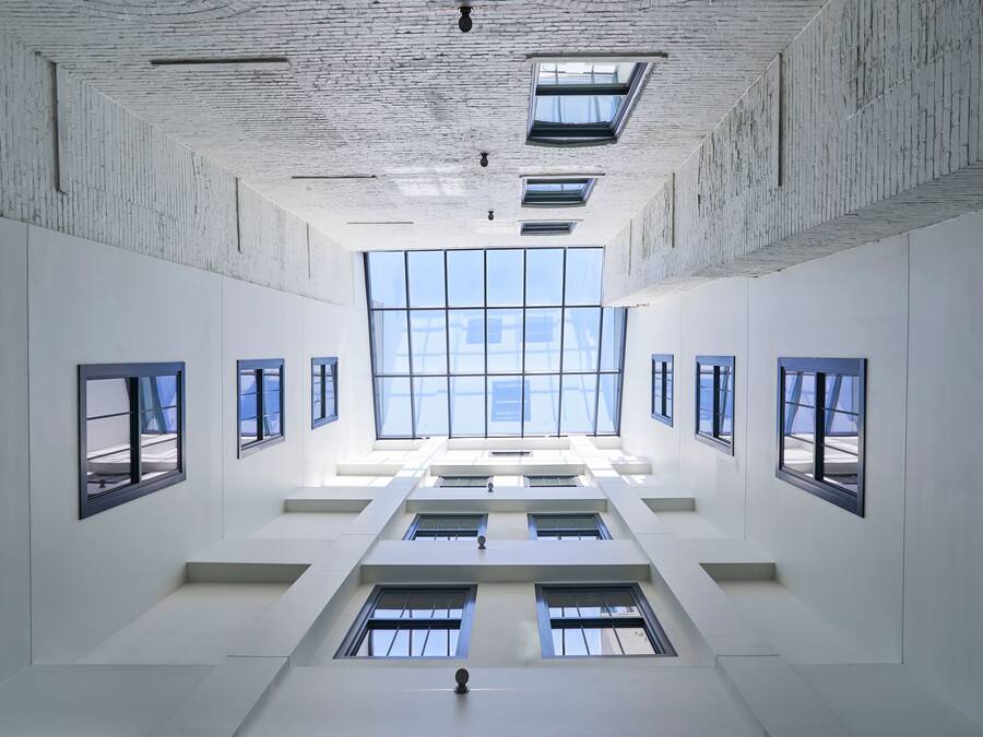 A spacious atrium with high ceilings and skylights, featuring a central open area with multiple windows and a symmetrical layout.