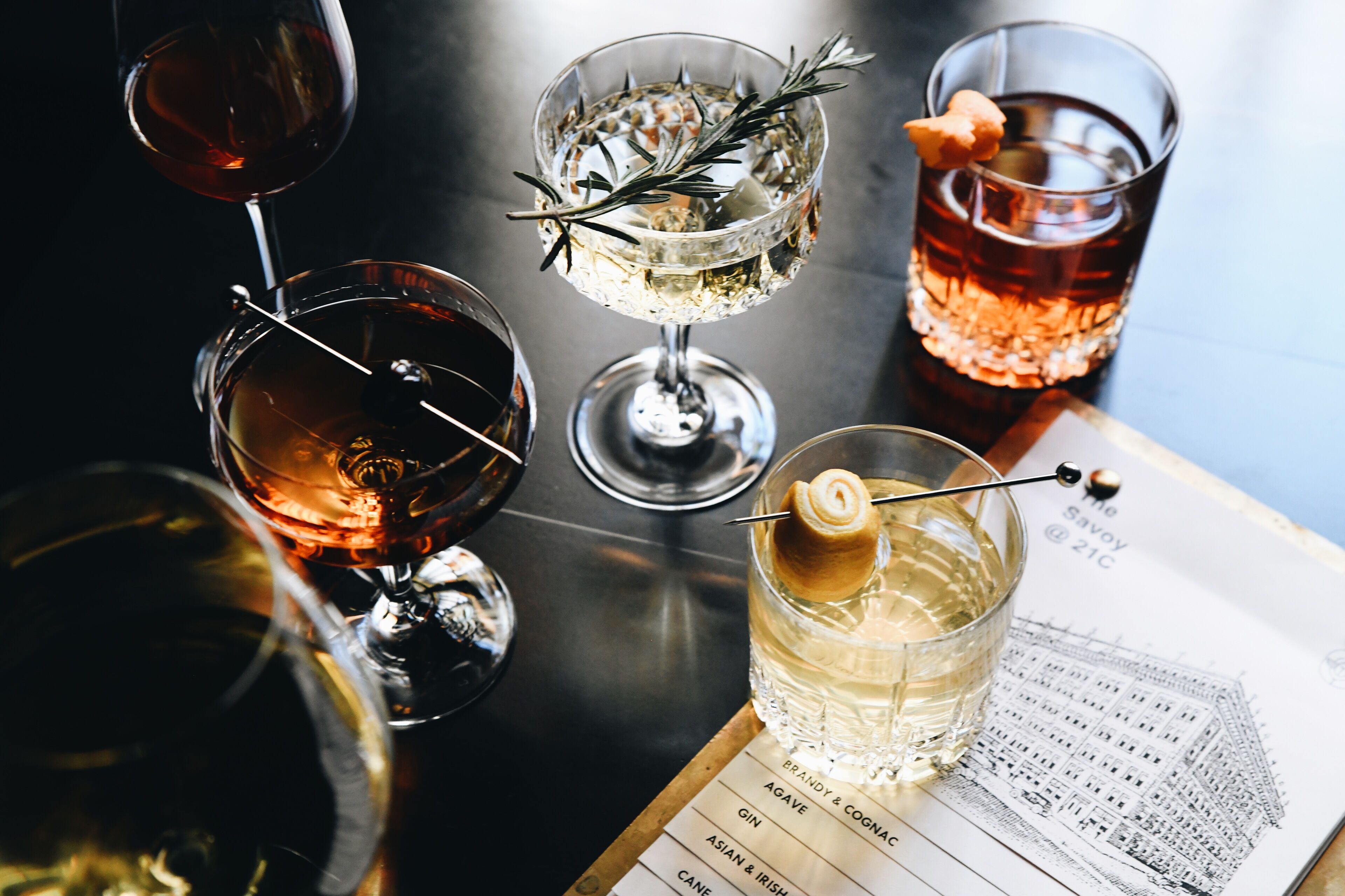 A variety of glasses with different beverages, a menu, and a book with a building illustration.