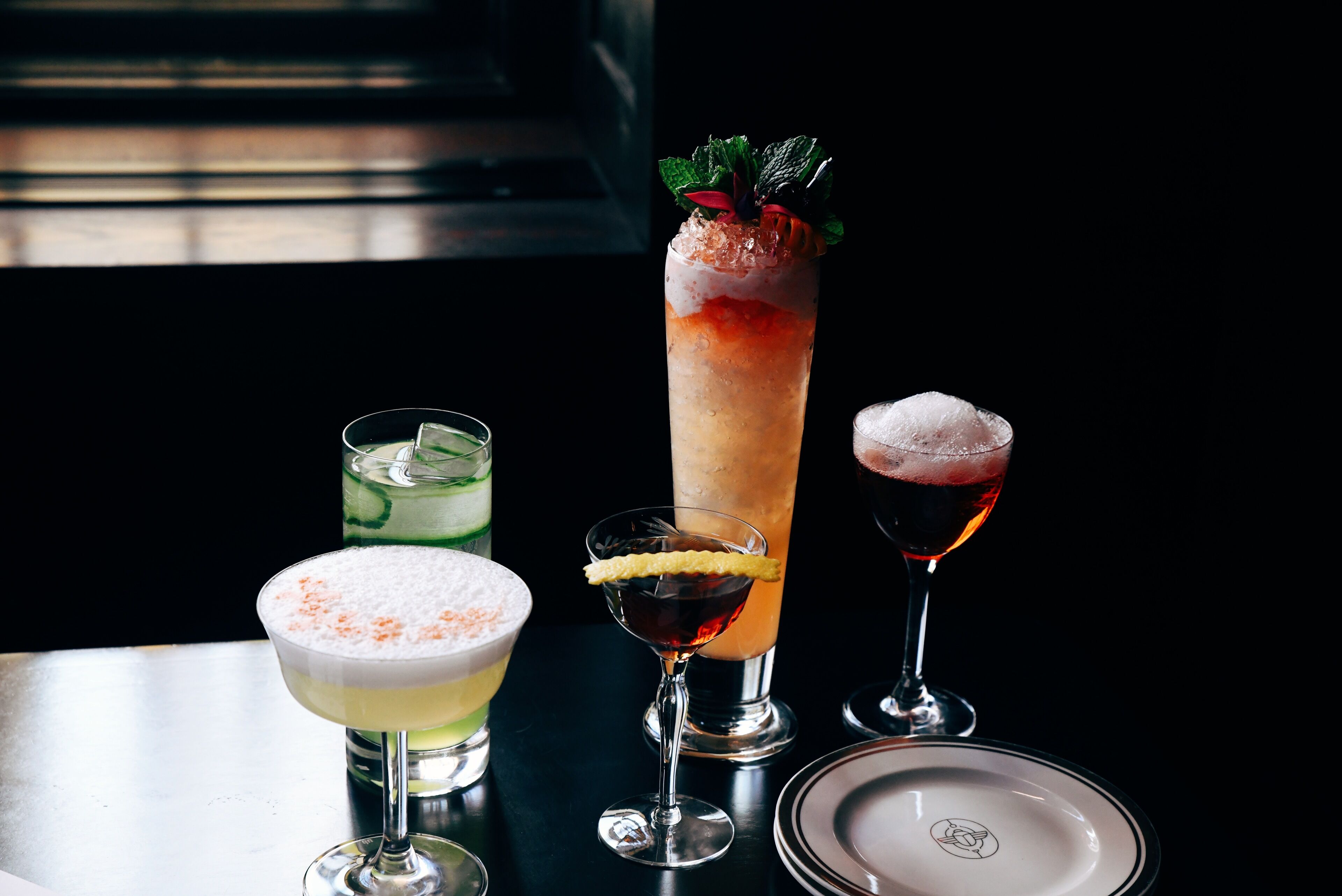 A variety of cocktails on a table with a black background.