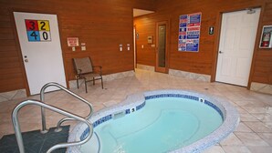 Un espace piscine comprenant un jacuzzi, une chaise et une porte indiquant l’emplacement des interrupteurs d’arrêt d’urgence.