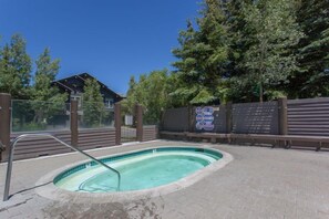 A swimming pool with a metal ladder, surrounded by a brick patio and a wooden fence. - Snowcreek 883 Phase V (Mammoth Lakes)