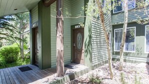 A green house with a wooden porch, a front door, and a mailbox. - Snowcreek 883 Phase V (Mammoth Lakes)