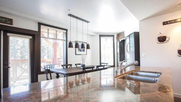 A modern kitchen with a central island, a built-in oven, and a stainless steel sink.