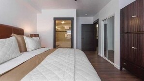 A bedroom with a large bed, a wardrobe, and a door leading to a bathroom.