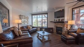 A living room with a fireplace, leather sofas, and a large window.