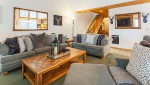 A cozy living room with two grey sofas, a wooden coffee table, and a staircase leading to an upper level. - Val d'lsere 21 (Mammoth Lakes)