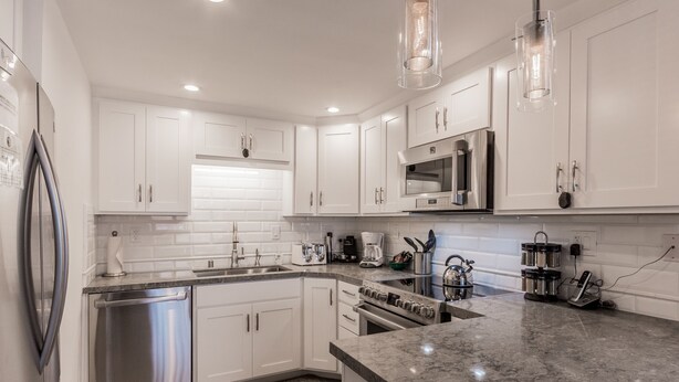 A modern kitchen with white cabinets, stainless steel appliances, and a granite countertop. - Val d'lsere 21 (Mammoth Lakes)