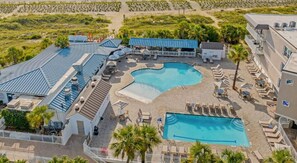 A resort with a large pool, sun loungers, and a covered area with umbrellas.