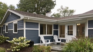 A two-story house with a covered porch, a front door, and a small garden with hydrangeas and a pathway leading to the house. - Best Coast Cottage - Just a block and a half to the beach!!! (South Haven)