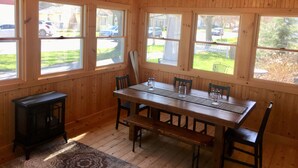 A wooden-paneled room with a dining table, chairs, and a small black stove. - Best Coast Cottage - Just a block and a half to the beach!!! (South Haven)