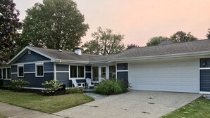 A two-story house with a covered porch, a garage, and a front lawn. - Best Coast Cottage - Just a block and a half to the beach!!! (South Haven)