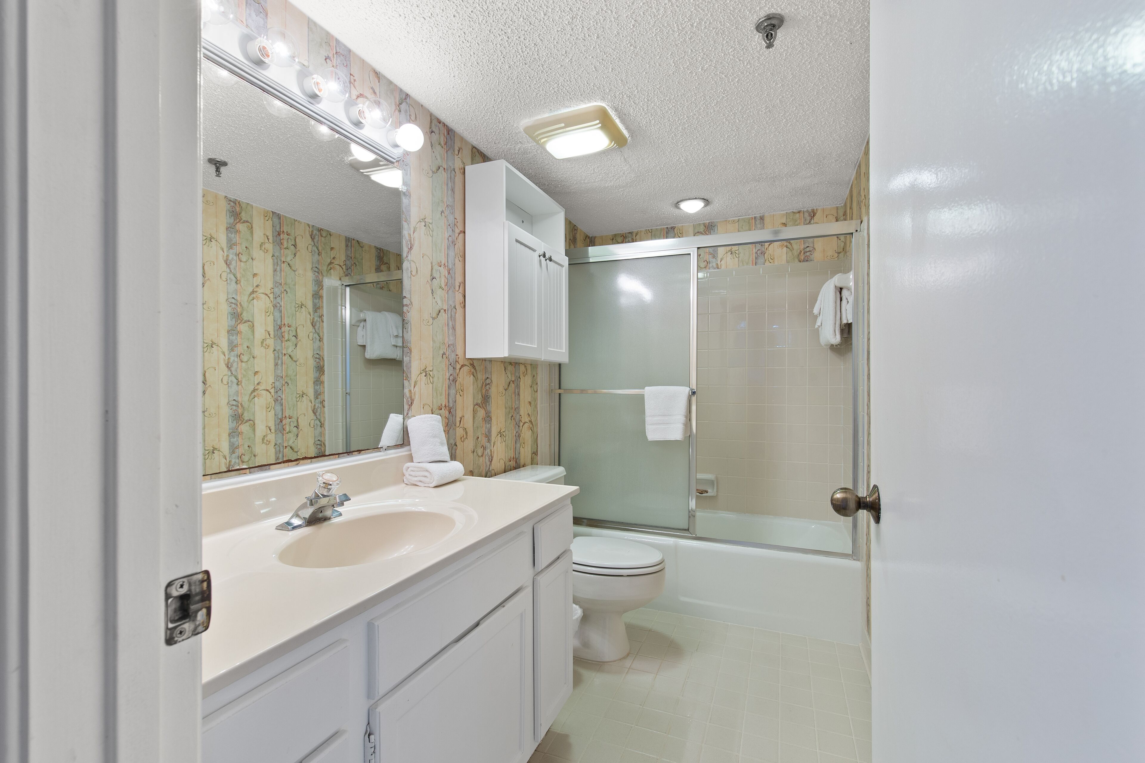 A bathroom with a sink, toilet, and shower area.