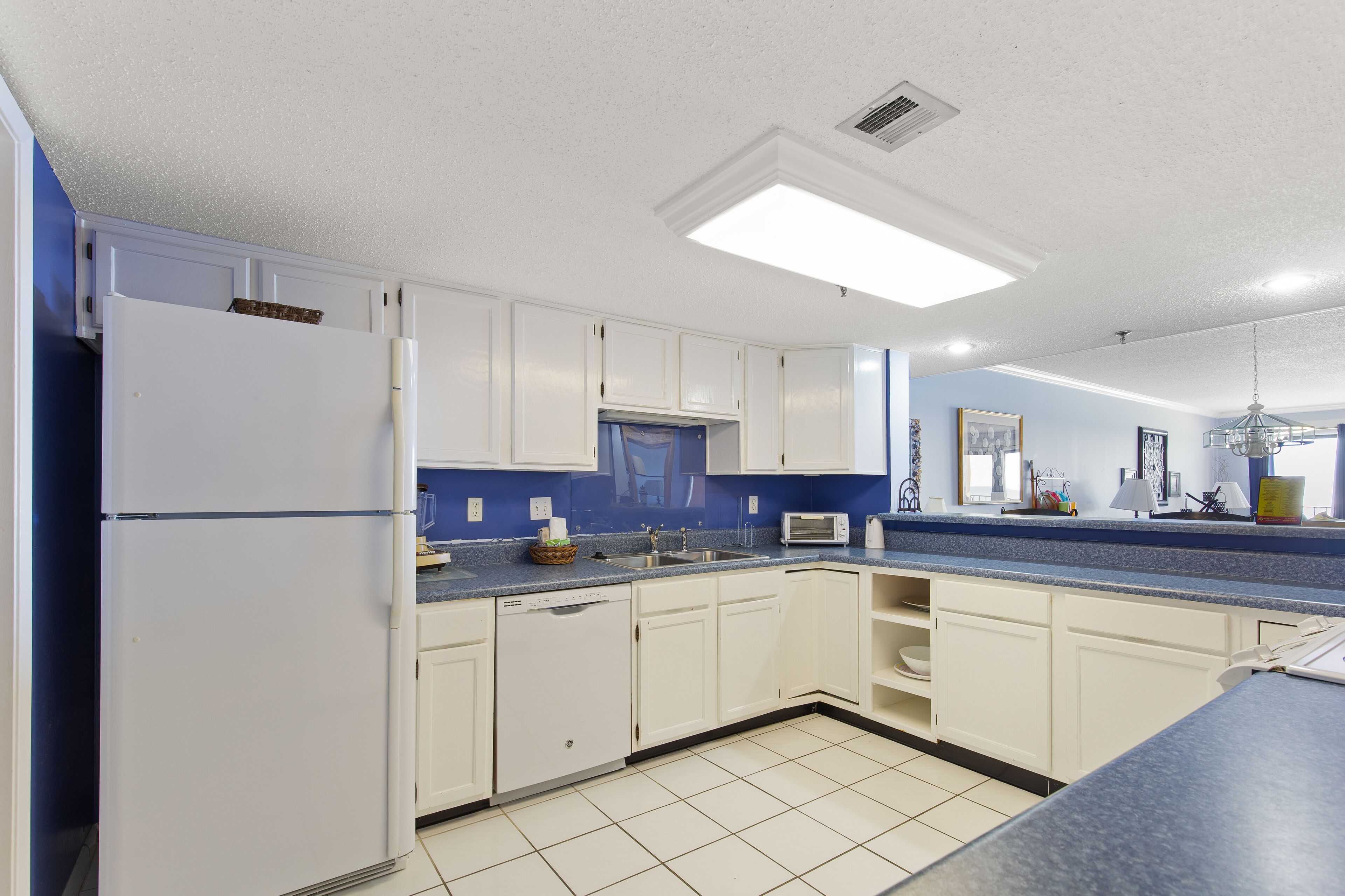 A kitchen with white cabinets, a blue countertop, a dishwasher, and a microwave.
