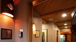 En hall med träbjälkar, en bänk och en väggmonterad lampa.