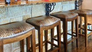 A bar area with wooden stools, a stone counter, and pendant lighting. - The LonePine in YellowHouse Canyon (Slaton)