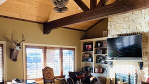 A spacious living room with a stone fireplace, leather sofas, and a mounted deer head. - The LonePine in YellowHouse Canyon (Slaton)