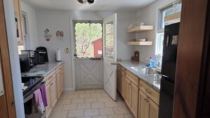 Une cuisine avec des meubles de rangement en bois, un four encastré, un évier et un réfrigérateur.