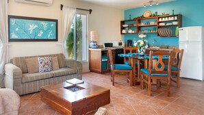 A living room with a sofa, coffee table, and dining area with chairs and a table.